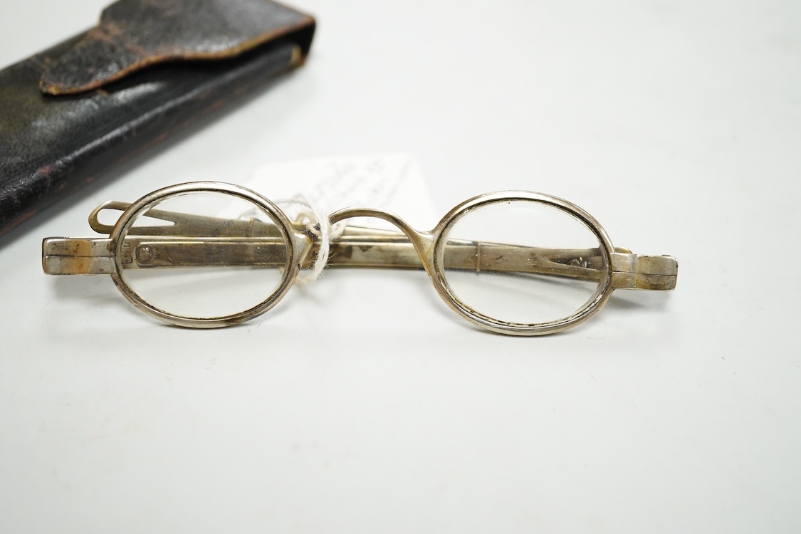 A pair of American ‘coin’ silver spectacles, first half 19th century by McAllister, Philadelphia, with slider sides, stamped inside McALLISTER PHILAD- and to the exterior hinge ‘JA 13’, unmarked leather and card case